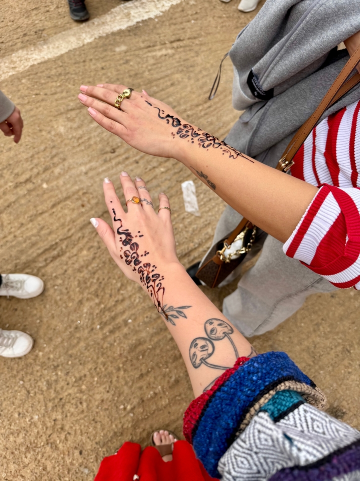 Two hands with henna tattoos touching.