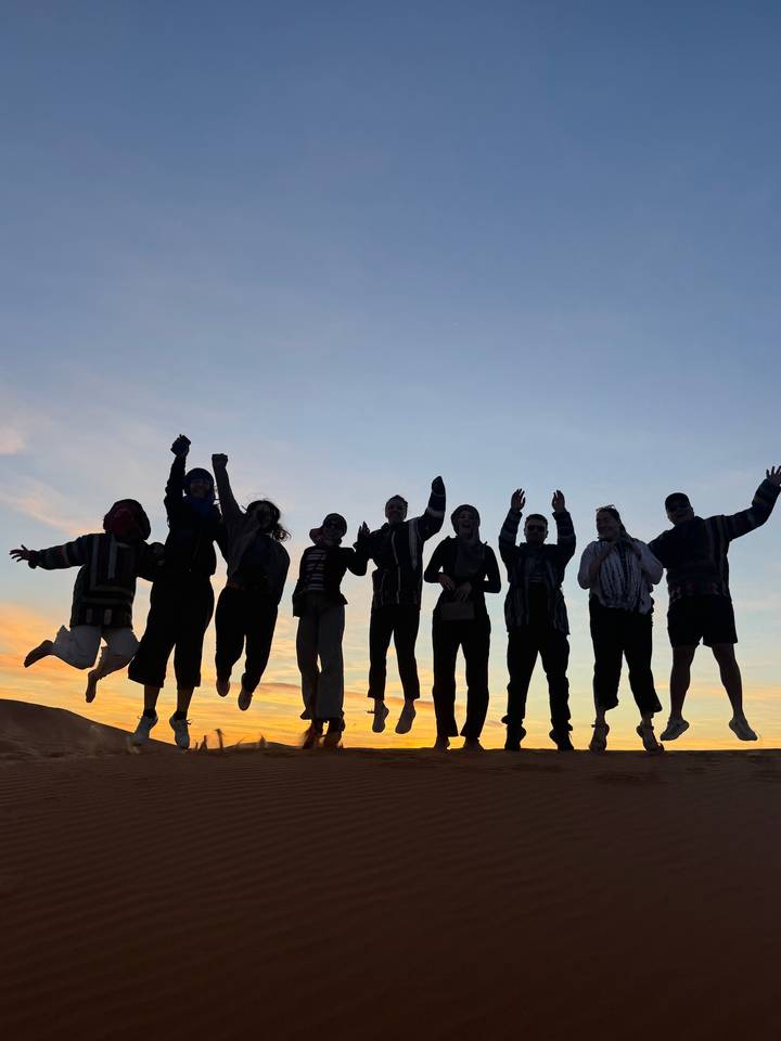 Silhouette of people jumping in the desert at sunset.