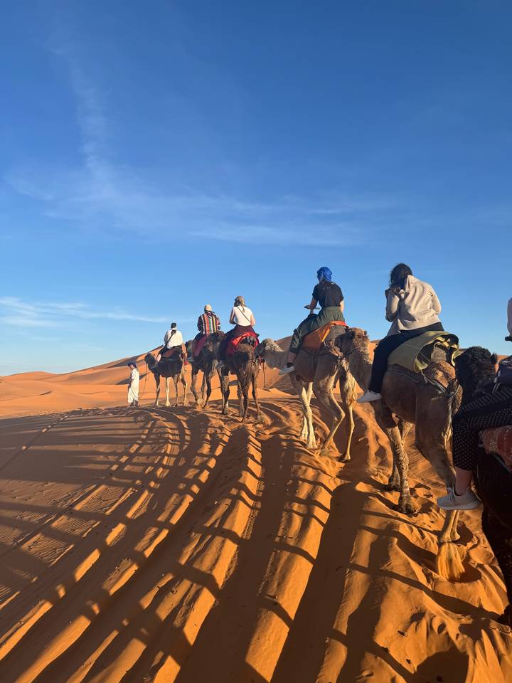 People riding camels in the desert.
