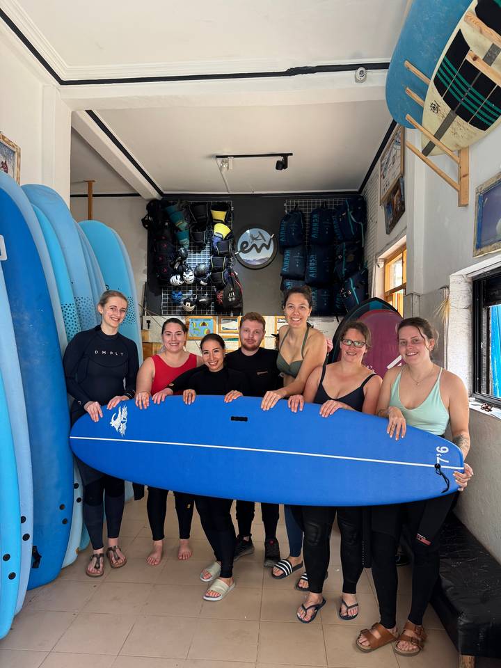 Group of people holding a surfboard indoors.