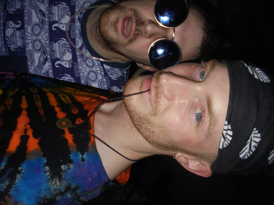 Close-up selfie of two friends in party attire under nightclub lighting.