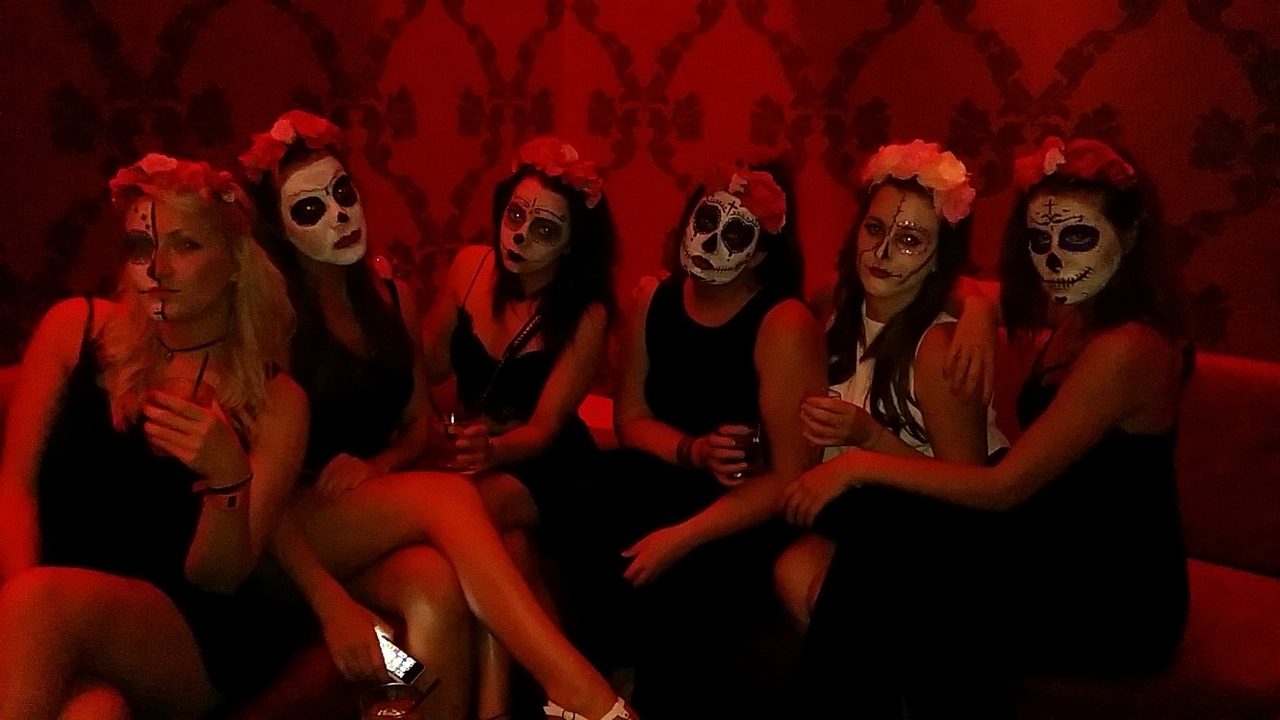 People with face paint sitting indoors with red lighting.
