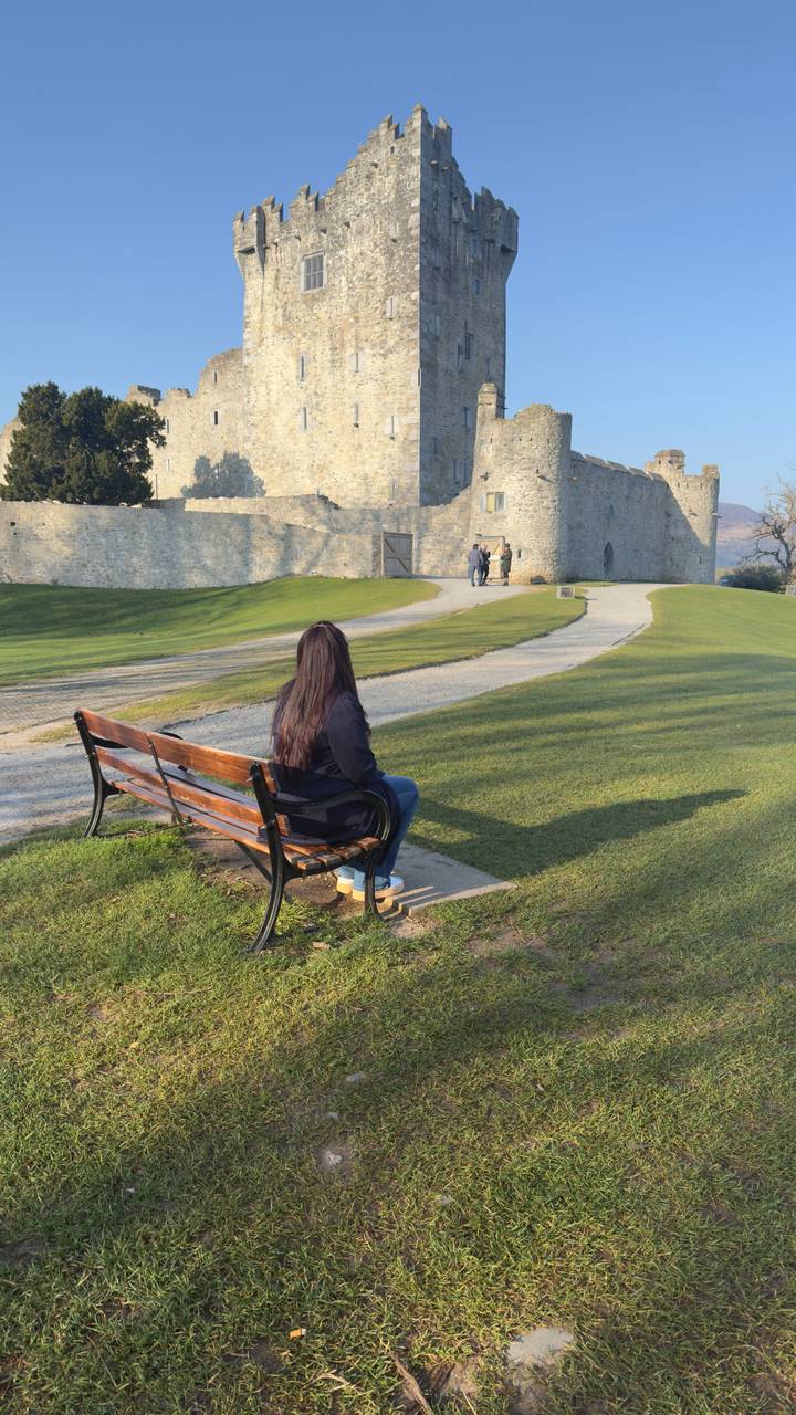 Person sitting on a bench near a medieval structure