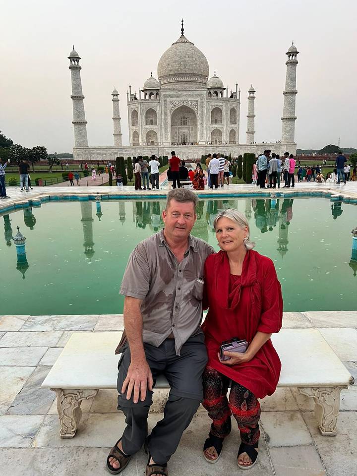 Twee mensen die bij een reflecterend bassin bij de Taj Mahal zitten.