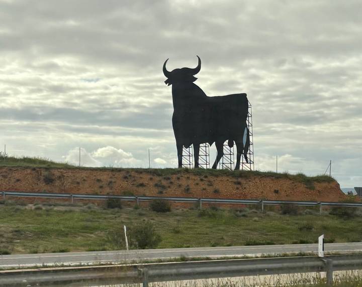 Large bull silhouette sculpture on a hill.
