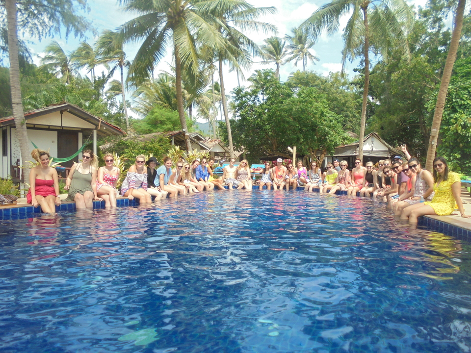 Large group sitting along the edge of a pool.