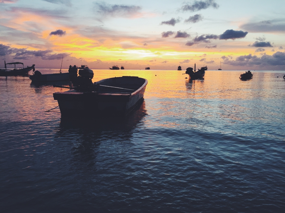 Boats floating on a calm sea during a splendid sunset.