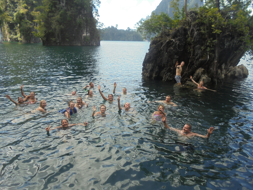 People swimming in a scenic lake surrounded by rocky cliffs.