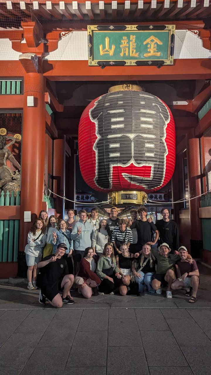 A group standing under a large red lantern at night.