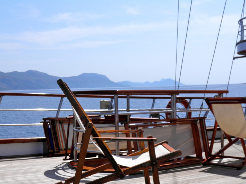 View from a boat deck towards the sea and distant islands.