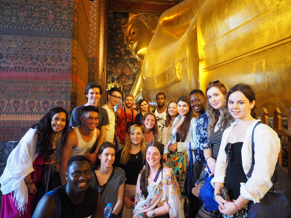 Group in front of a golden reclining Buddha statue.