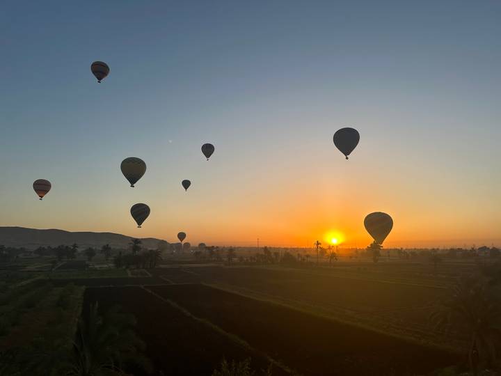 Heteluchtballonnen tijdens zonsopgang boven een landschap.