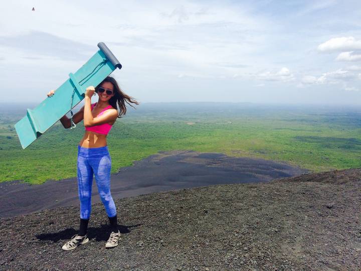 Person holding a sandboard on a volcanic area.