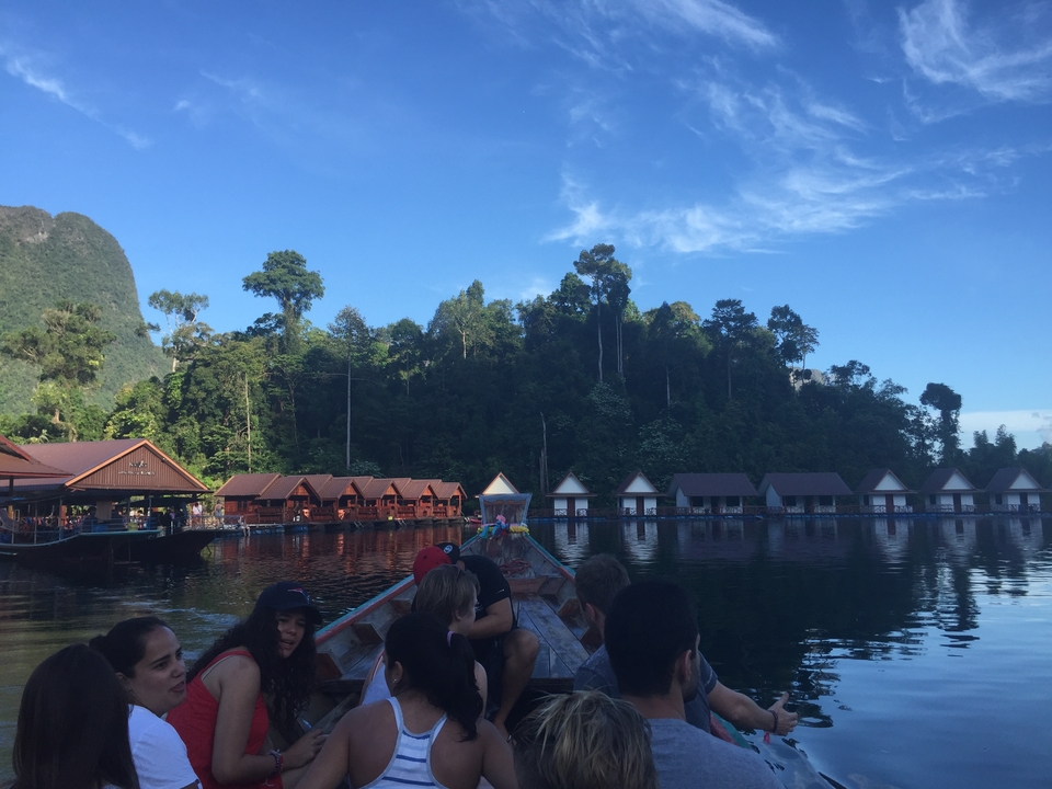 People on a boat with floating houses in the background.