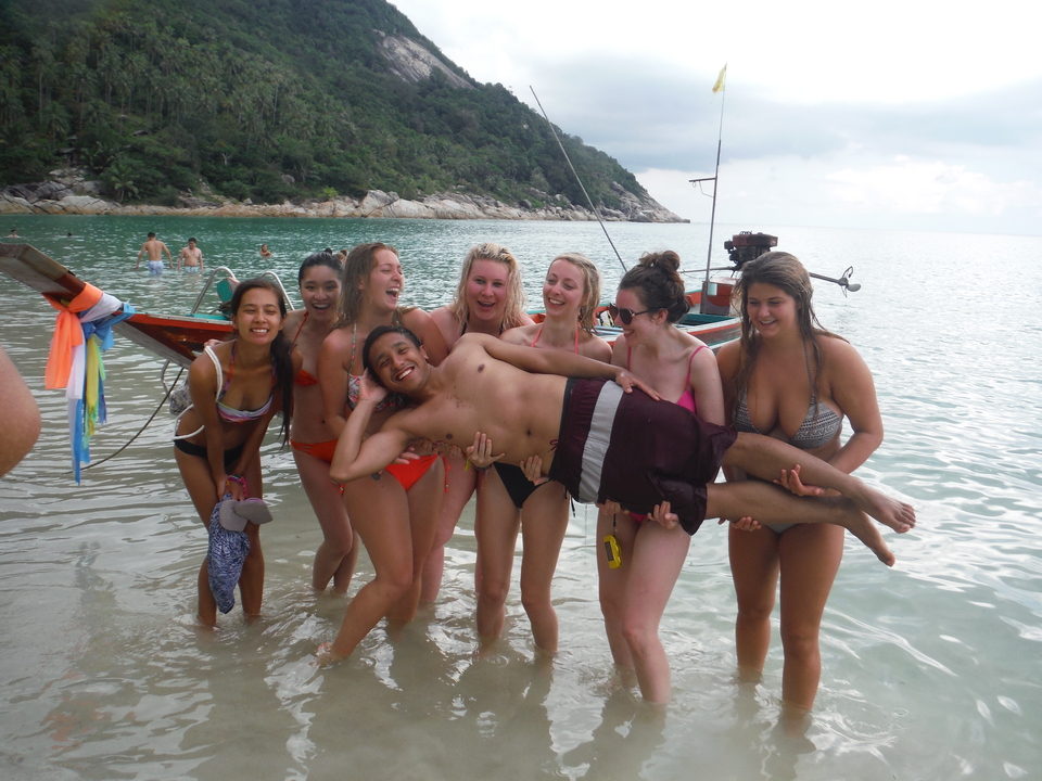 People posing together by a beach.