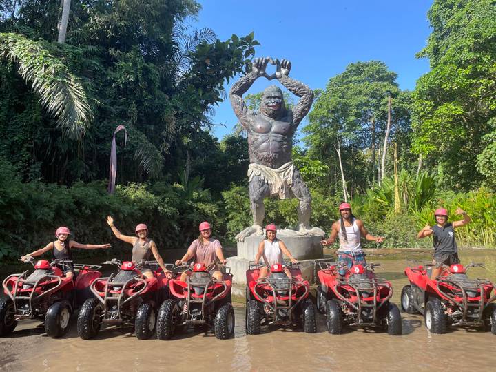 Group of people on ATVs in front of a giant statue.