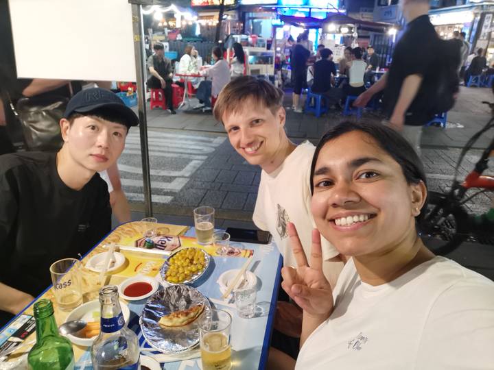 Group of friends enjoying food and drinks at an outdoor market.