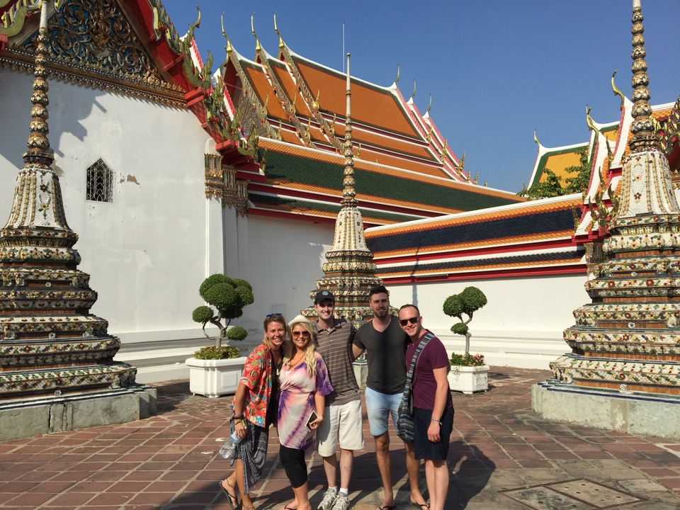 Five people posing in front of a temple with intricate architecture.