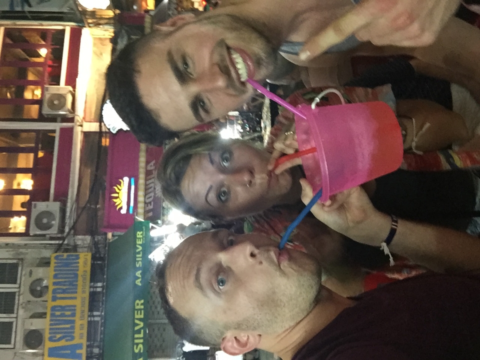 A close-up of friends drinking from a large pink bucket.