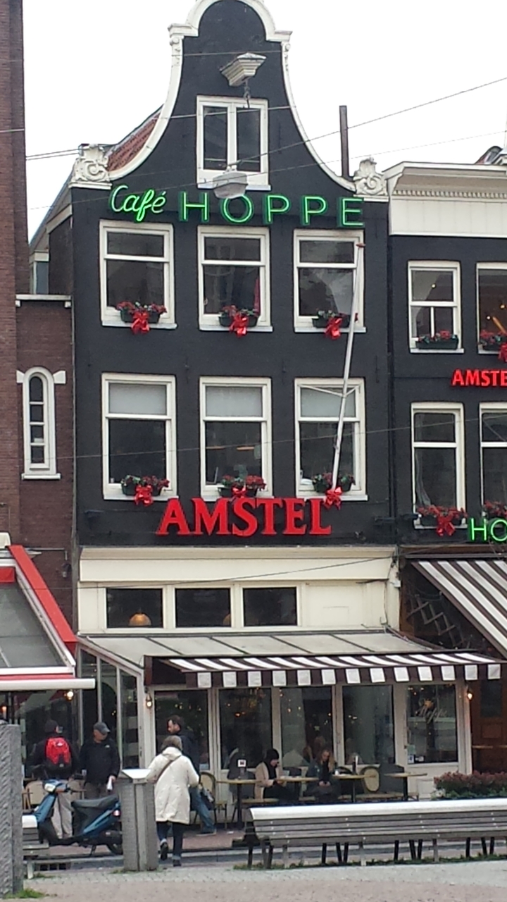 Building facade with 'AMSTEL' sign and flower boxes.