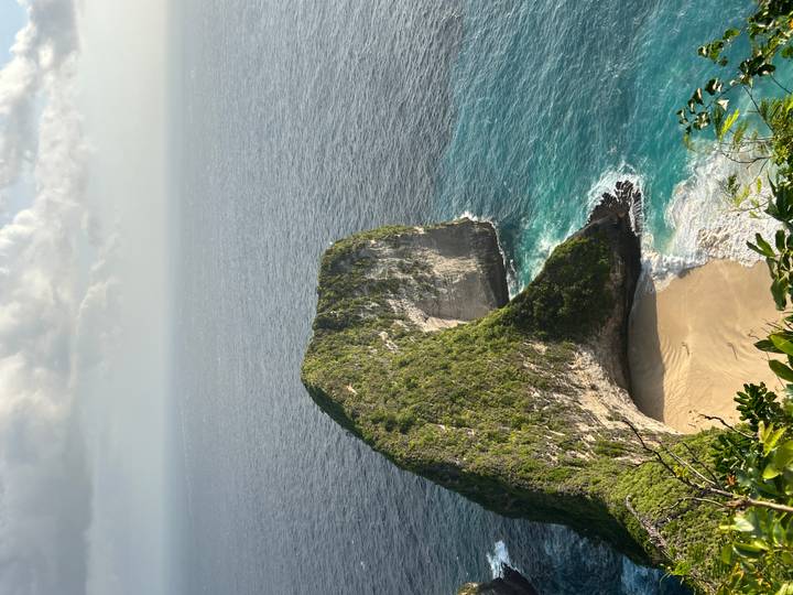 Coastal cliffs with white sandy beach and turquoise water.