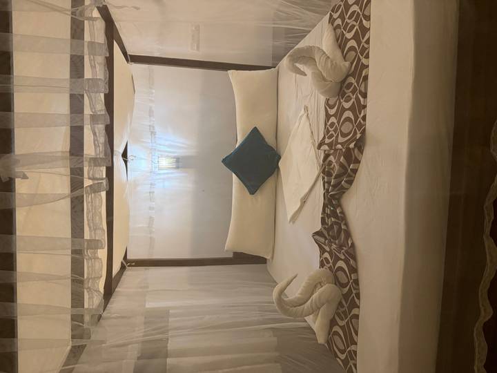 Intérieur simple d'une chambre avec un lit décoré de cygnes en serviettes.