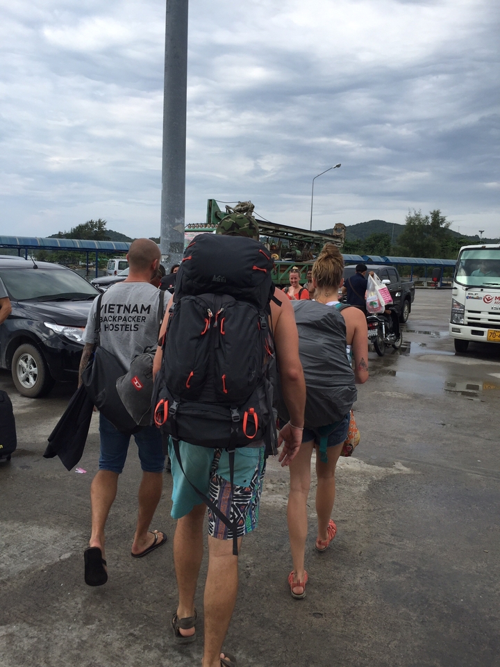 Travelers with backpacks walking towards vehicles.