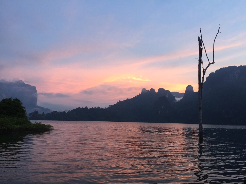 A beautiful sunset over a serene lake with silhouette hills.