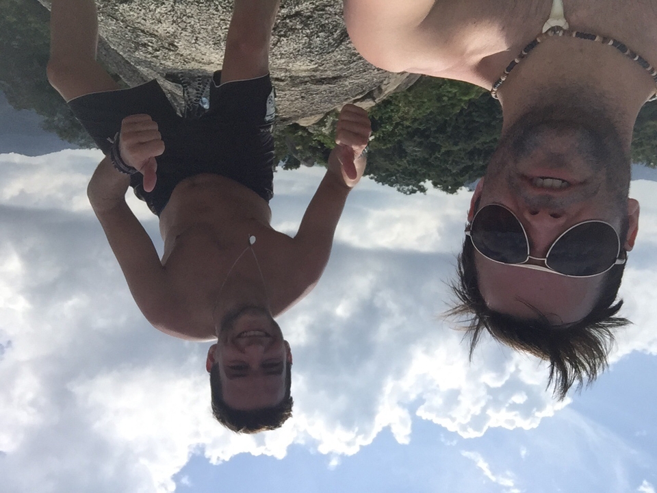 Two friends posing on rocks with thumbs up.