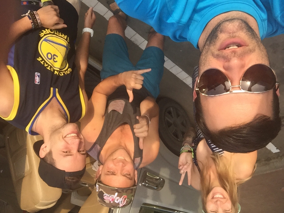 Friends posing and gesturing with smiles near a vehicle.