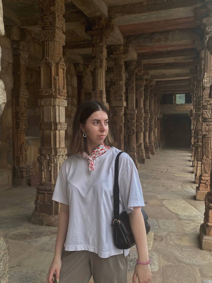 Woman standing in a historic stone corridor.
