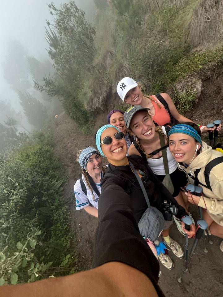 Groupe de randonneurs souriants posant sur un sentier de montagne brumeux.