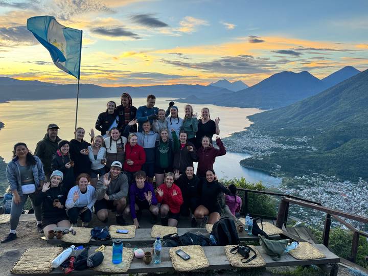 Grande photo de groupe avec vue sur un lac et des montagnes au coucher du soleil.