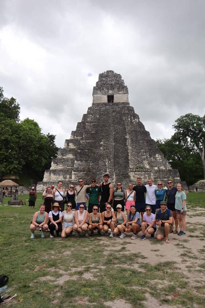 Grand groupe posant devant une ancienne pyramide maya.