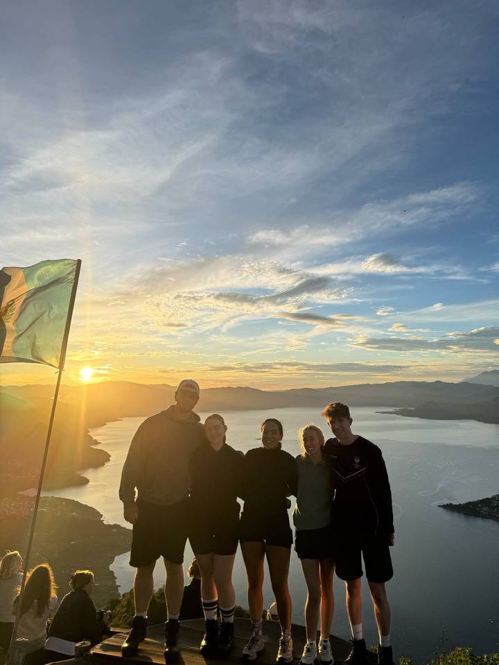 Groupe de personnes debout avec un drapeau au lever du soleil sur un lac.