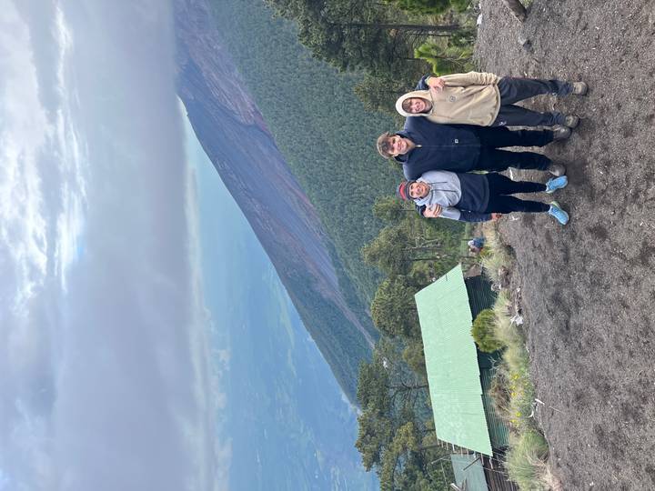 Trois personnes qui posent dans un lieu en altitude avec une vue sur la montagne.