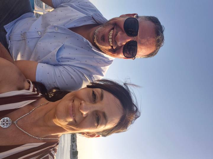 Twee mensen die glimlachen buitenshuis met een heldere blauwe lucht.