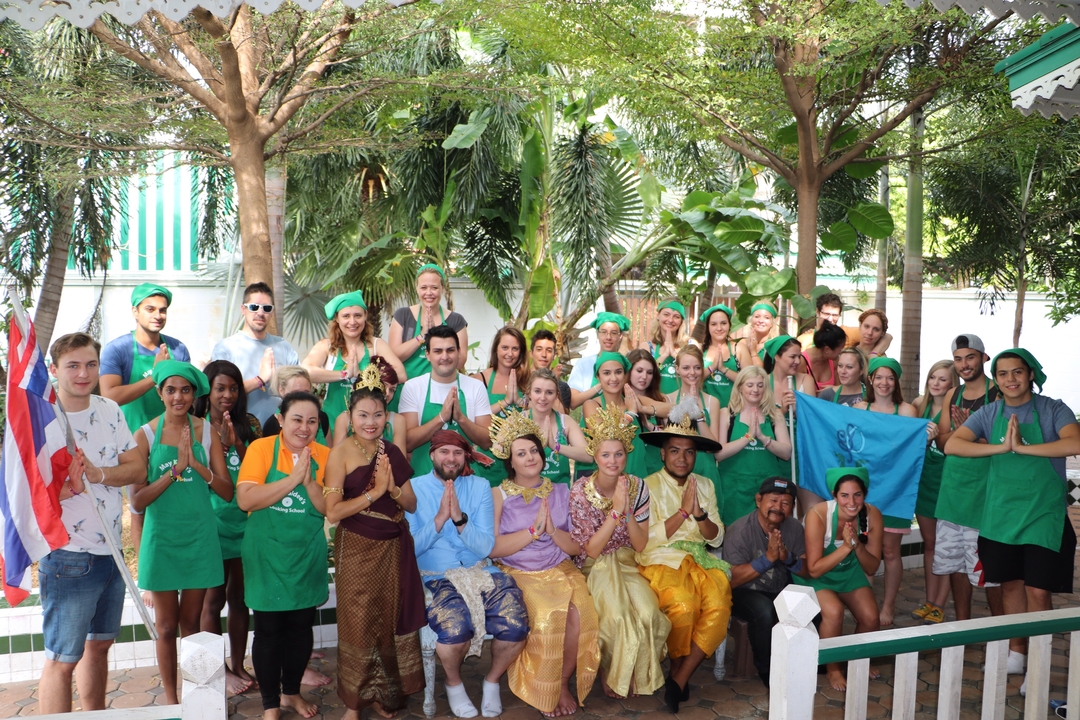 A group of people dressed in costumes and aprons posing outdoors with trees in the background.