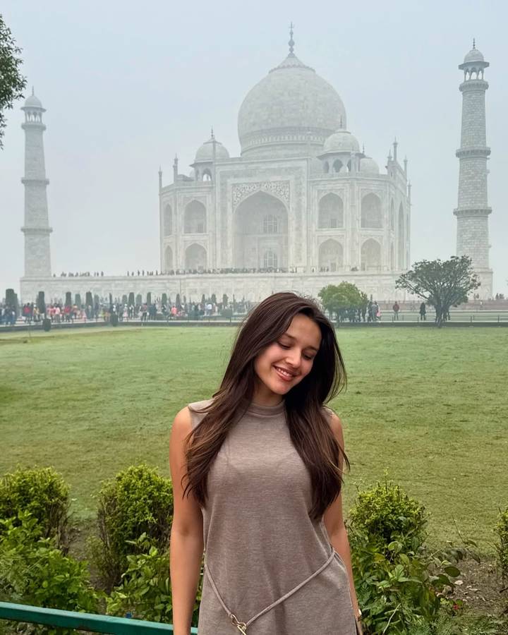 Personne souriante avec le Taj Mahal en arrière-plan.