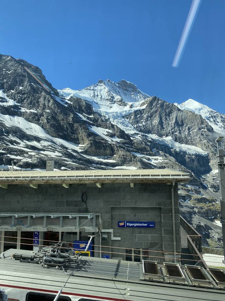 Mountain train station with snowy peaks.