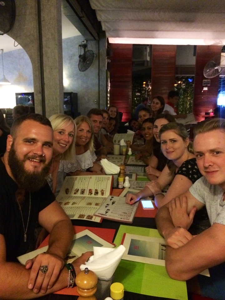 Travel group seated at a long table browsing menus in a restaurant.