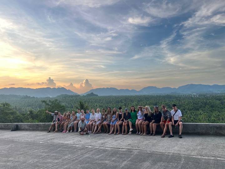 Groupe de personnes assises sur un point de vue panoramique avec des montagnes.