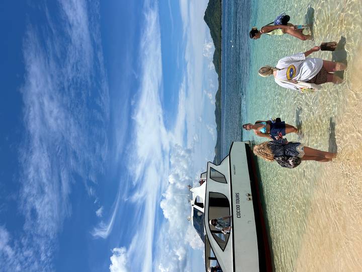 Des personnes débarquant d'un bateau sur une plage de sable.