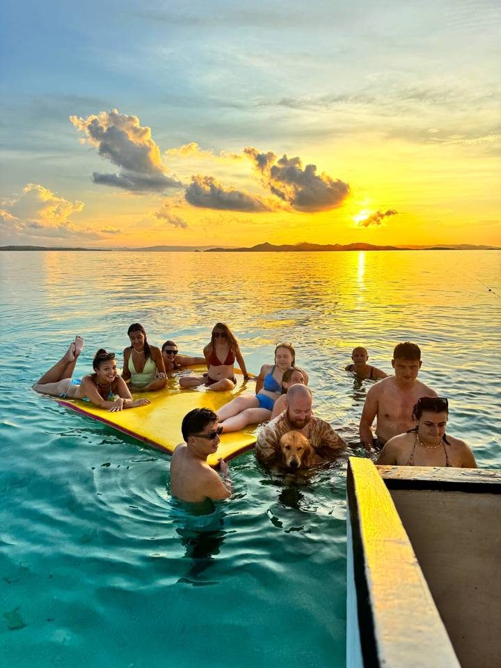 Groupe de personnes se détendant sur un matelas flottant au coucher du soleil