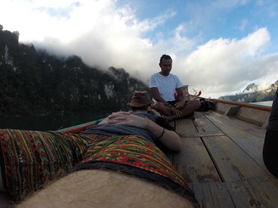 Two people resting on a boat with scenery of rocky mountains.