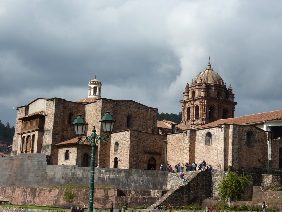 Historic stone building with people walking nearby.