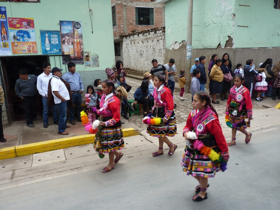 People in traditional costumes parading on a street.