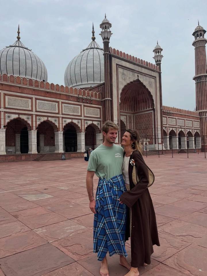 Un couple debout devant un bâtiment historique orné.