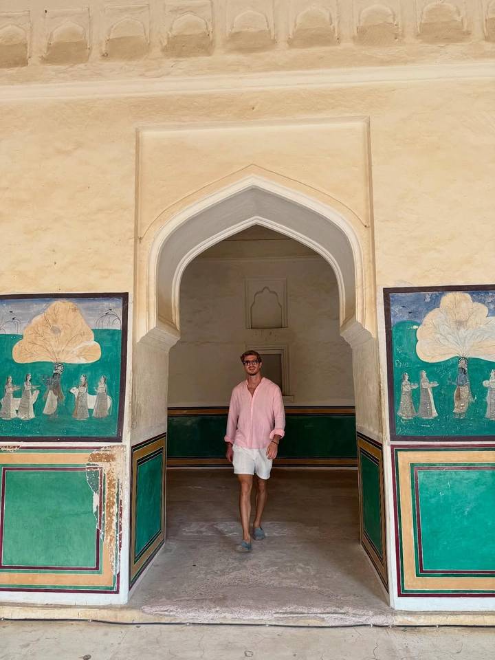 Homme debout devant une entrée historique décorée.
