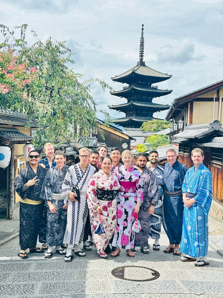 A group of people in traditional attire with a pagoda in the background.